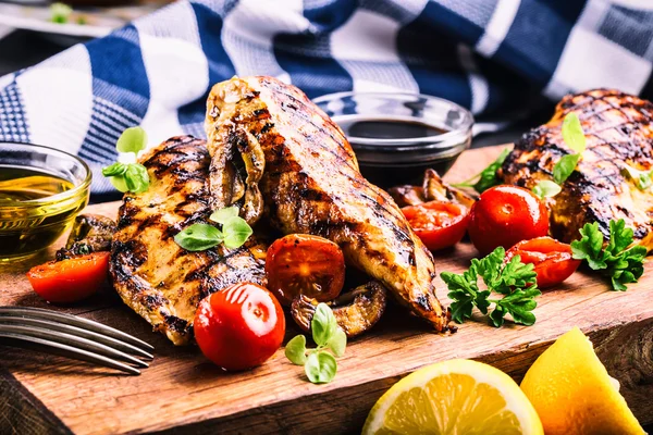 Grilled chicken breast in different variations with cherry tomatoes,  mushrooms, herbs, cut lemon on a wooden board or teflon pan. Traditional cuisine. Grill kitchen — Stock Photo, Image