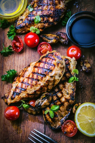 Grillat kycklingbröst i olika varianter med körsbärstomater, svamp, örter, skuren citron på en träskiva eller teflonpanna. Traditionellt kök. Grillkök — Stockfoto