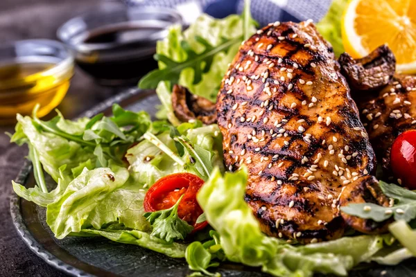 Peito de frango grelhado em diferentes variações com salada de alface tomates cereja cogumelos ervas cortam limão em uma tábua de madeira ou panela de teflon. Cozinha tradicional. Cozinha grelhada — Fotografia de Stock