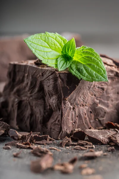 Chocolate. Black chocolate. A few cubes / blocks of black chocolate with mint leaves. Chocolate slabs spilled from grated chockolate powder — Stock Photo, Image