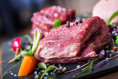 Biftek.Biftek. Et.Porsiyonluk et. Çiğ taze et. Sığır filetosu bifteği. T-Bone bifteği. Böğür bifteği. Ördek göğsü. Sebze dekorasyonu. Bir restoran veya otel mutfağında işlenmek için hazırlanmış porsiyonlu et