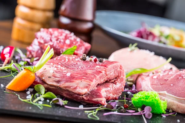 Steak.Beef steak.Meat.Portioned meat.Raw fresh meat.Sirloin steak.T-Bone steak. Flank steak. Duck breast. Vegetable decoration. Portioned meat prepared for processing in a restaurant or hotel kitchen