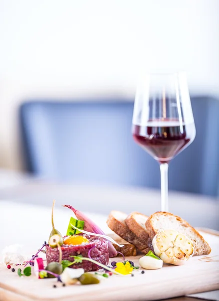 Raw beef .Tasty Steak tartare. Classic steak tartare on wooden board. Ingredients: Raw beef meat salt pepper egg garlic chili herb decoration toast bread and cup of red wine — Stock Photo, Image