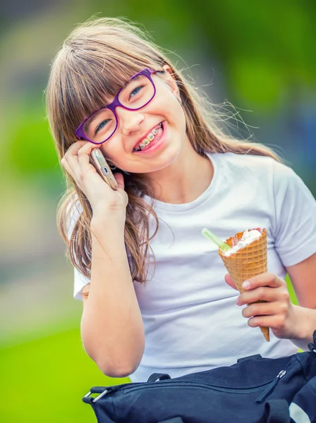 Cute little girl in the park on a sunny day with ice cream and mobile phone — Stock Photo, Image
