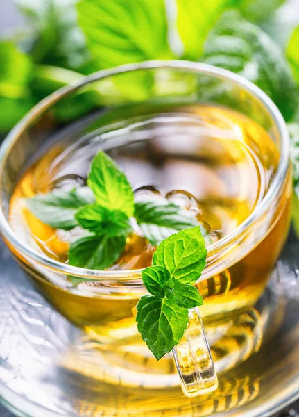 Té. Té de menta. Té de hierbas. Hoja de menta. Hojas de menta. Té en una taza de vidrio, hojas de menta, té seco, lima en rodajas. té de hierbas y hojas de menta en un plato de pizarra en un restaurante o salón de té —  Fotos de Stock