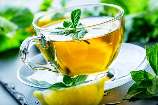 Чай. Мятный чай. Травяной чай. Мятный лист. Мятные листья. Чай в стакане, мятные листья, сушеный чай, нарезанный лайм. травы чай и мятные листья на табличке с шифер в ресторане или чайная комната — стоковое фото