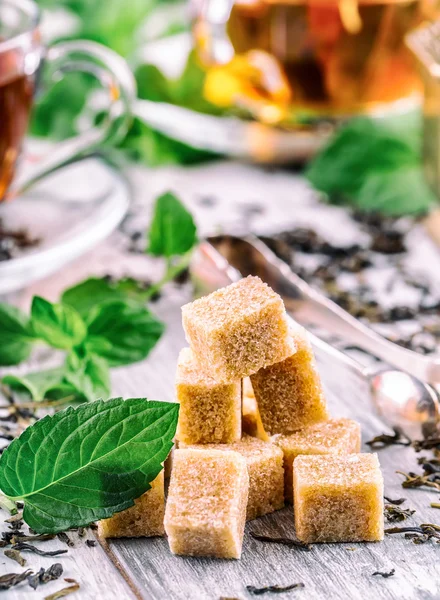 Sugar. Cane sugar. Cane sugar cubes heap close up macro shot. Tea in a glass cup, mint leaves, dried tea, sliced lime, cane brown sugar