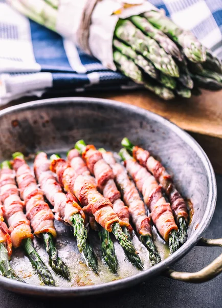 Sparris. Sparris och rulle bacon. Grillad sparris med rullad bacon och stekt ägg. Stekt gammal stekpanna full med rullad bacon med grön sparris och stekt ägg — Stockfoto