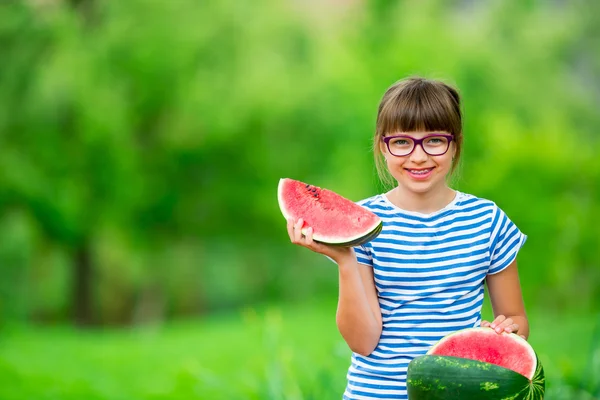 Niño comiendo sandía. Los niños comen frutas en el jardín. Pre adolescente en el jardín sosteniendo una rebanada de sandía. niña feliz comiendo sandía. Niña con gases y aparatos ortopédicos — Foto de Stock