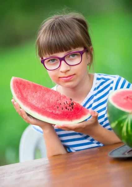 Child eating watermelon. Kids eat fruits in the garden. Pre teen girl in the garden holding a slice of water melon. happy girl kid eating watermelon. Girl kid with gasses and teeth braces