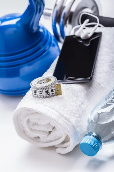 Fitnessgeräte. Kettlebell-Handtuchhanteln Wasser-Smartphone mit Kopfhörer und Maßband — Stockfoto