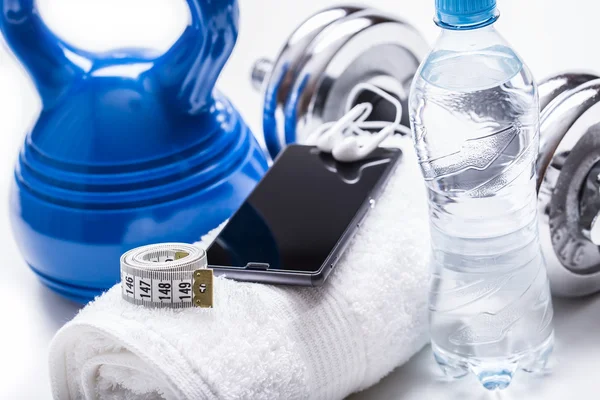 Fitnessgeräte. Kettlebell-Handtuchhanteln Wasser-Smartphone mit Kopfhörer und Maßband — Stockfoto