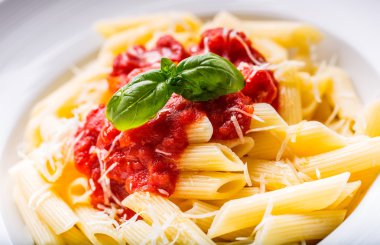 Domates Bolonez Soslu Makarna Penne, Parmesan Peyniri ve Fesleğen Yaprakları. Akdeniz yemekleri. İtalyan mutfağı