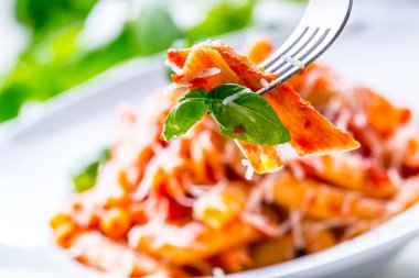 Domates Bolonez Soslu Makarna Penne, Çatal üzerinde Parmesan Peyniri ve Fesleğen. Akdeniz yemekleri. İtalyan mutfağı.