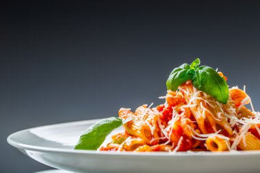 Domates Bolonez Soslu Makarna Penne, Parmesan Peyniri ve Fesleğen Yaprakları. Akdeniz yemekleri. İtalyan mutfağı