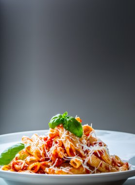 Domates Bolonez Soslu Makarna Penne, Parmesan Peyniri ve Fesleğen Yaprakları. Akdeniz yemekleri. İtalyan mutfağı