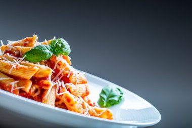 Domates Bolonez Soslu Makarna Penne, Parmesan Peyniri ve Fesleğen Yaprakları. Akdeniz yemekleri. İtalyan mutfağı