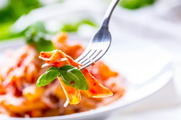 Pasta Penne con salsa boloñesa de tomate, queso parmesano y albahaca en un tenedor. Cocina Mediterránea.Cocina italiana . — Foto de Stock