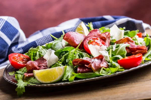 Bresaola de vaca seca. Salada bresaola arugula bebê espinafre tomates limão e queijo parmesão — Fotografia de Stock