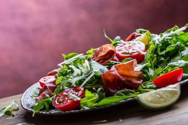 Getrocknete Rindfleischbresaola. Salat Bresaola Rucola Baby Spinat Tomaten Limette und Käse Parmesan — Stockfoto