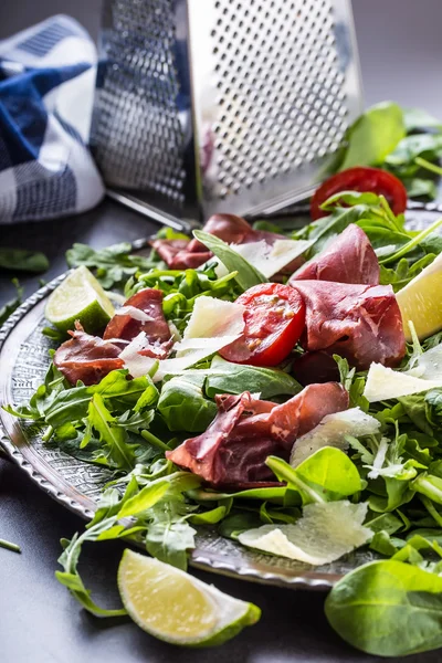 Suszona wołowina bresaola. Sałatka arugula bresaola pomidorki szpinak z limonki i ser parmezan — Zdjęcie stockowe