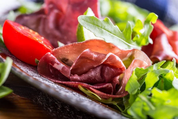 Torkat nötkött bresaola. Sallad bresaola ruccola baby spenat tomat lime och ost parmesan — Stockfoto