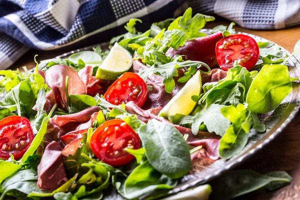 Suszona wołowina bresaola. Sałatka arugula bresaola pomidorki szpinak z limonki i ser parmezan — Zdjęcie stockowe