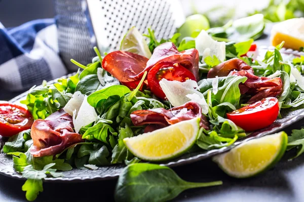 Dried beef bresaola. Salad bresaola arugula baby spinach tomatoes lime and cheese parmesan — Stock Photo, Image