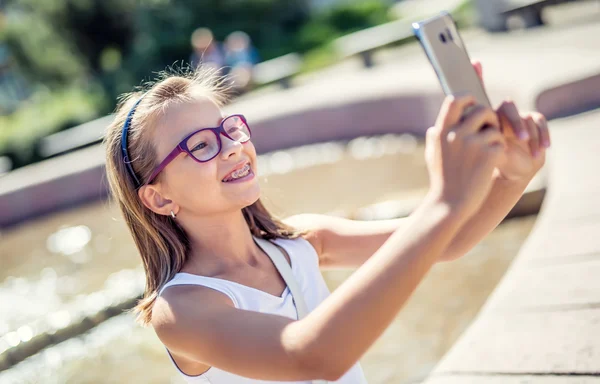 Selfie. Bella ragazza carina con bretelle e occhiali ridere per un selfie — Foto Stock
