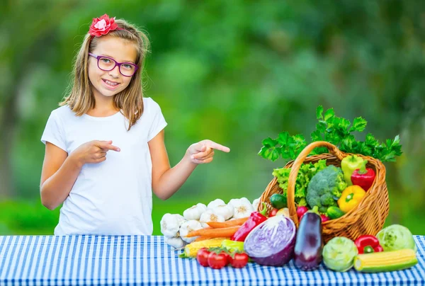 Linda joven en la mesa llena de verduras surtido. Fondo borroso en el jardín. Pre-adolescente youn chica con gafas y dientes frenos — Foto de Stock