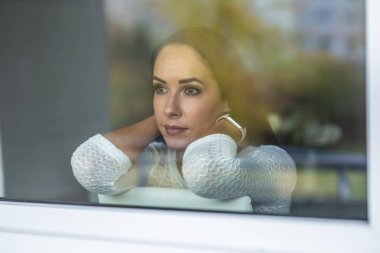 Pencerenin arkasında oturan genç bir kadın tarafından izolasyon üzüntüsü..