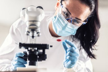 Laboratuar teknisyeni, aşı ve ilaç icadı için yapılan araştırmalar sırasında Coronavirus 'a karşı bir kan örneğini inceliyor..