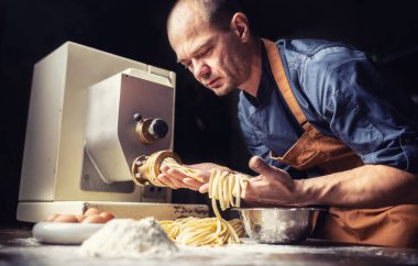 Pastaiolo şefi taze makarna hamurundan şeritler yapıyor..