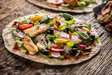 Salata, turp, domates, zeytin, nar ve ızgara haloumi peynirli vejetaryen tortilla..