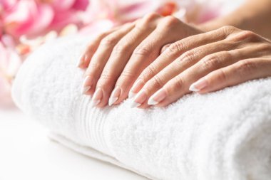 Yumuşak beyaz bir havluya yerleştirilmiş kadın elleri manikür kaplıcasına çivilenmeye hazır..