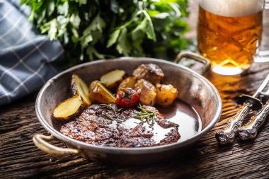 Metalik kase ve bira ile servis edilen klozetli fırınlanmış domuz eti..