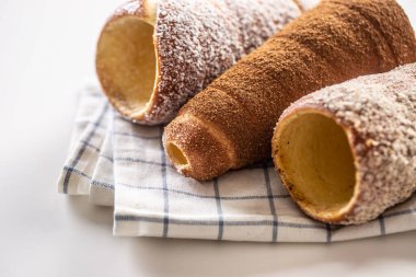 Beyaz kareli kumaş üzerinde vanilyalı hindistan cevizi ve tarçın trdelnik.