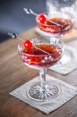 Manhattan klasik kokteyli. Viski, vermut, angostura aromatik acı ve vişneli garnitürlü kısa içecek aperatifi..