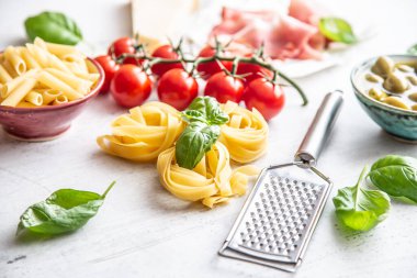 İtalyan makarnası için çeşitli malzemeler. Domates, jambon, zeytin, fesleğen ve peynir rendesi de dahil..