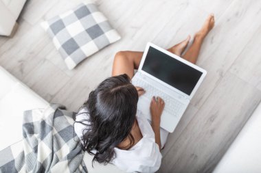 Sadece beyaz gömlekli bir kadının, yerde oturup dizlerindeki defter üzerinde çalışmasının en üst görüntüsü..