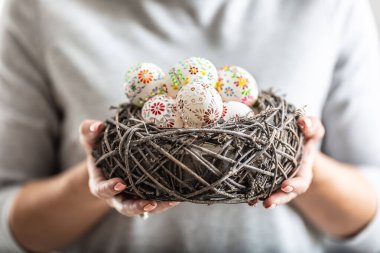 Kuş yuvası, kadınların elinde tutulan renkli paskalya yumurtalarıyla dolu..