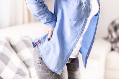 Kanepede oturan ve belini ağrıtan bir kadının ayrıntıları..