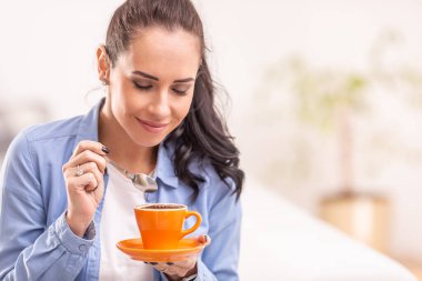Güzel bir kadın turuncu fincandan taze kahve kokusu alır..