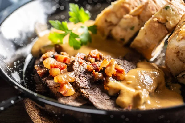 Typical Czech food svickova with beef slices, cream sauce and bread dumplings and fried bacon cubes.