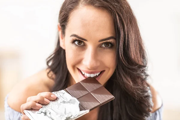 誘惑的に女性がチョコレートバーからビットを見て — ストック写真