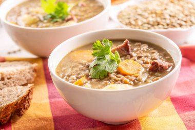 Lentil soup with pieces of smoked pork neck, carrots, potatoes and coriander. Traditional Slovak, Czech or Eastern European food.