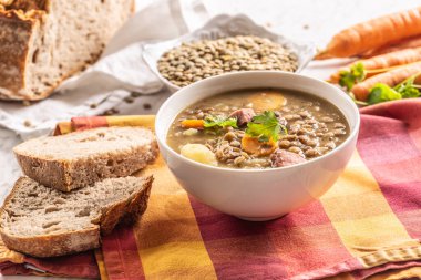 Lentil soup with pieces of smoked pork neck, carrots, potatoes and coriander. Traditional Slovak, Czech or Eastern European food.