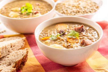 Lentil soup with pieces of smoked pork neck, carrots, potatoes and coriander. Traditional Slovak, Czech or Eastern European food.