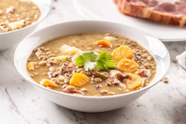 Lentil soup with pieces of smoked pork neck, carrots, potatoes and coriander. Traditional Slovak, Czech or Eastern European food.