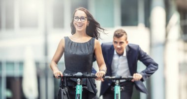 İki iş arkadaşı şehirde birbirini kovalayan elektrikli scooterlarla eğleniyor..